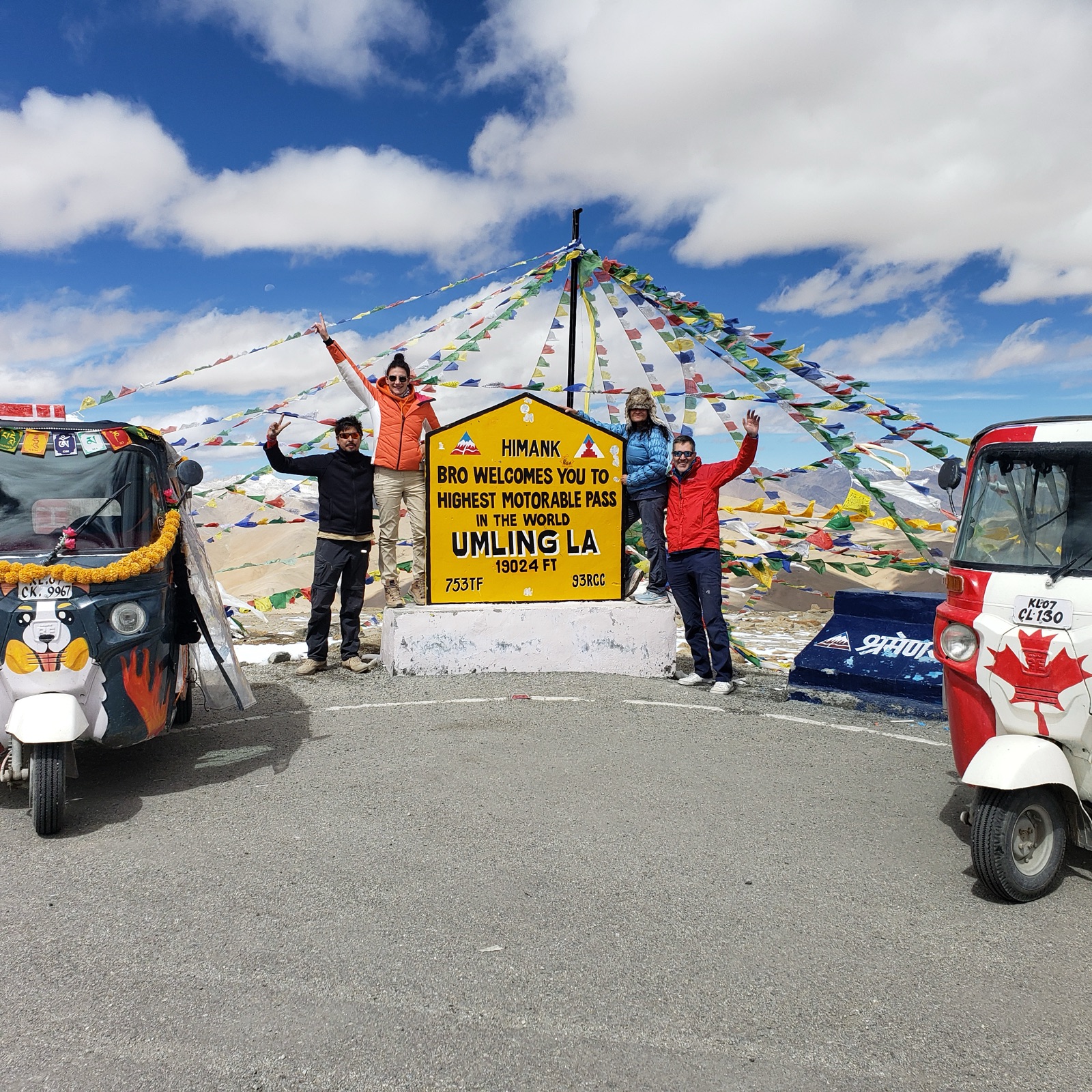 The Umling La summit sign at 5,799 m, with auto-rickshaws